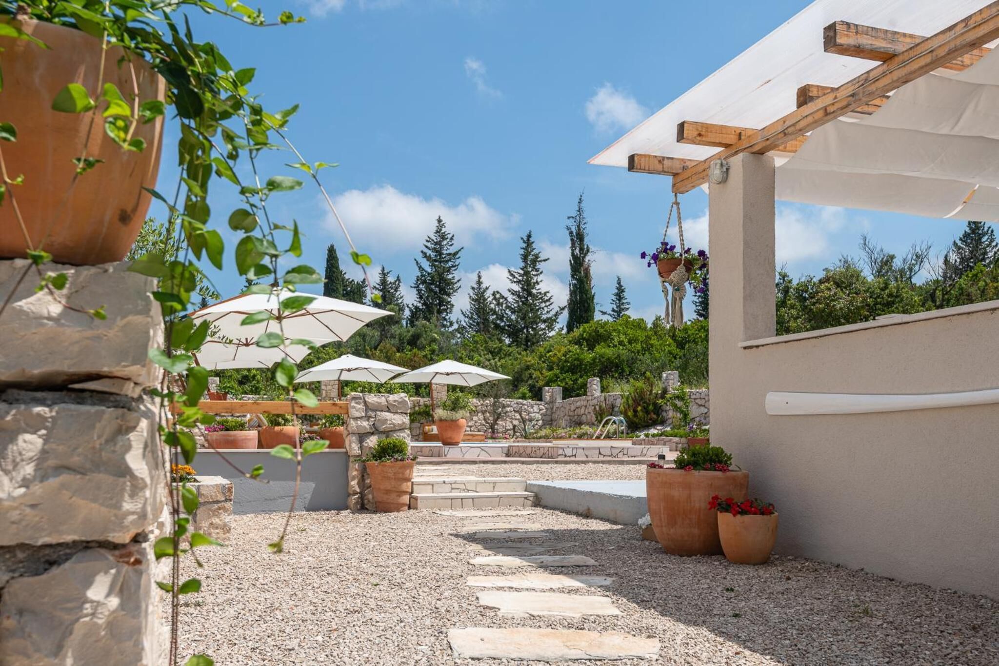 A patio area with stone steps, potted plants, and umbrellas.