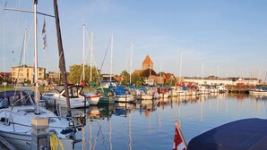 A marina with boats docked, a prominent building with a tower, and calm water reflecting the surroundings. - Awesome home in Askeby with sauna (Askeby)