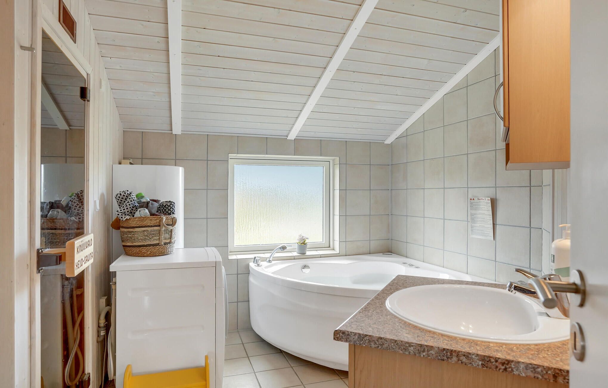 Ein modernes Badezimmer mit einer freistehenden Badewanne, einem Waschbecken und einem Fenster für natürliches Licht.
