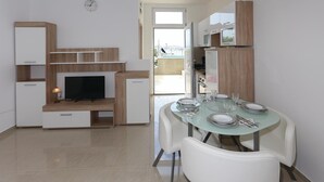 Une cuisine moderne avec un coin repas, comprenant un téléviseur, des placards et une table dressée pour quatre personnes.