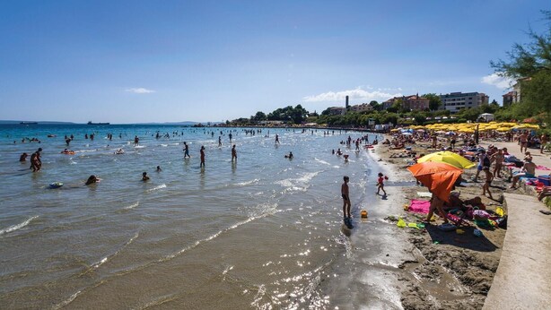 Une plage bondée où les gens se baignent et prennent des bains de soleil.