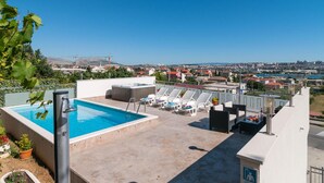 Une piscine sur le toit, dotée de chaises longues et d’un jacuzzi, offrant une vue panoramique sur la ville.