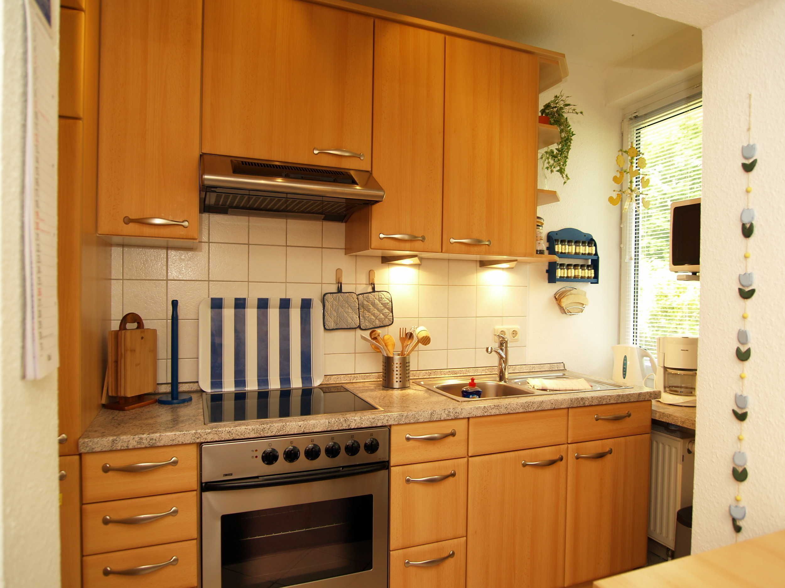 A kitchen with wooden cabinets, a stove, and a sink.