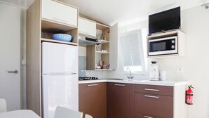 Une cuisine compacte équipée d’un réfrigérateur, d’un four à micro-ondes, d’une cuisinière et de placards.
