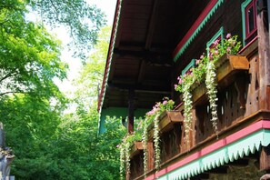 A traditional wooden building with balconies adorned with flowers, set in a lush green forest. - Spring - Room 1 - Forsthaus Leiner Berg (Dessau-Roßlau)