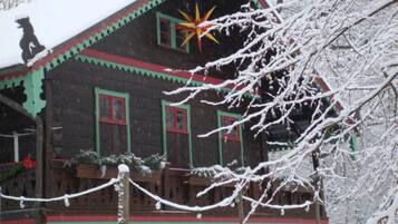 A wooden house with a snow-covered roof and a star decoration.