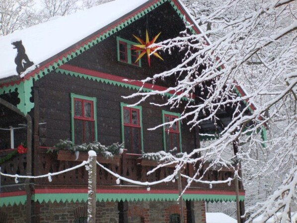 Une maison en bois avec un toit enneigé et une décoration en forme d’étoile.