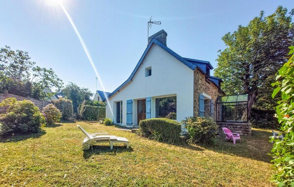 A house with a white exterior, blue shutters, and a stone foundation.