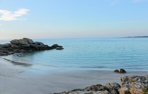 A coastal beach with large rocks and calm water.