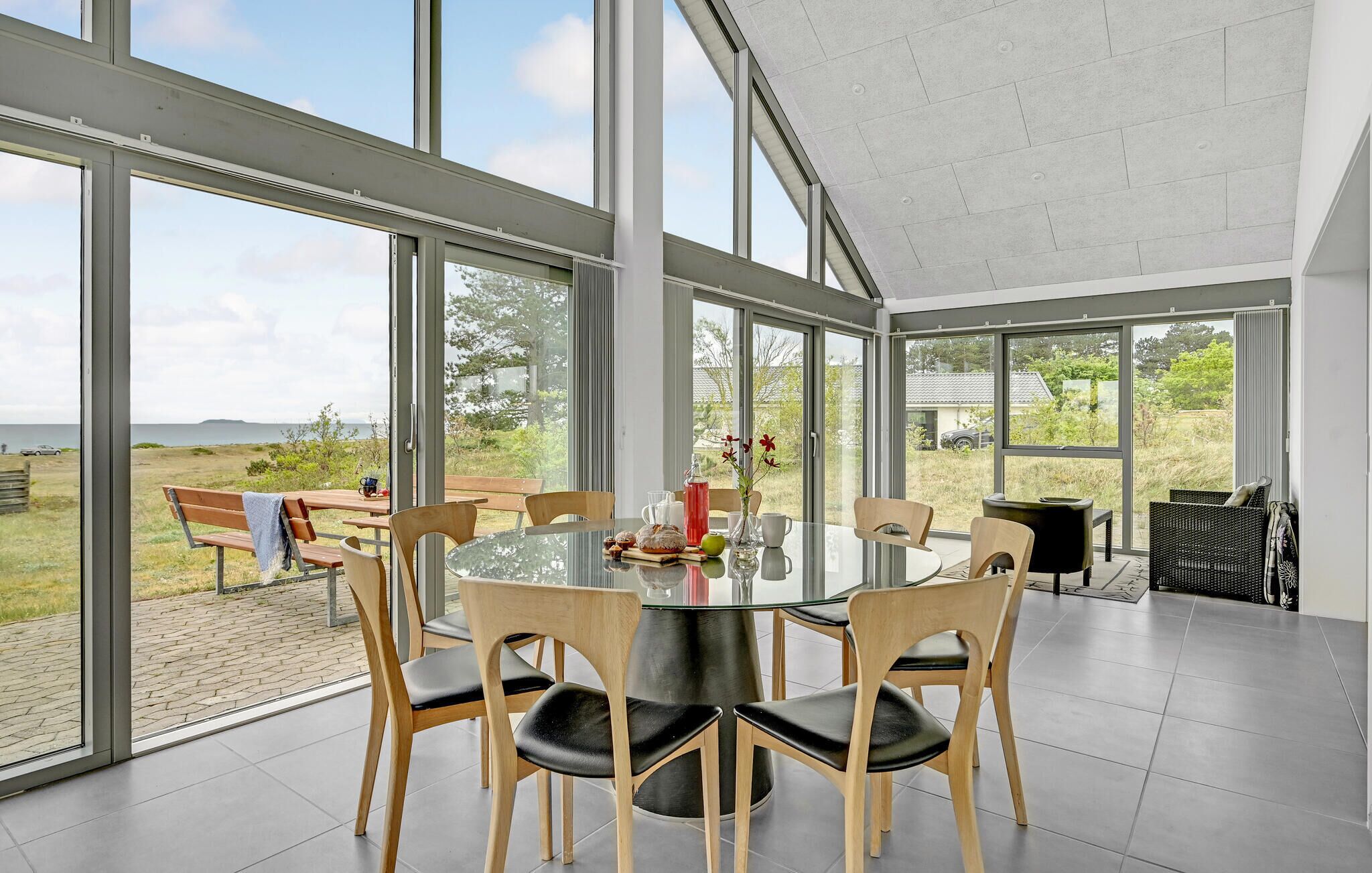 Un comedor moderno con una mesa redonda, sillas de madera y grandes ventanales que ofrecen vistas al exterior.
