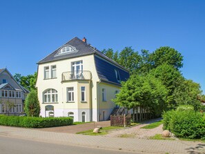 Ein zweistöckiges Haus mit Balkon, Auffahrt und einem gepflegten Garten.