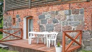 A stone building with a wooden deck, white plastic chairs, and a potted plant. - Pet friendly apartment in Retowo 4 (Retowo 4)