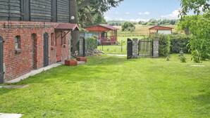 A well-maintained grassy yard with a brick building, a wooden structure, and a metal gate. - Pet friendly apartment in Retowo 4 (Retowo 4)
