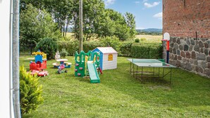 A grassy outdoor area with a playset, a small house, and a ping pong table. - Pet friendly apartment in Retowo 4 (Retowo 4)