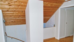 A wooden staircase leading to a loft bedroom with a sloped ceiling.
