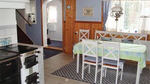 A kitchen with a stove, a dining table with chairs, and a window with curtains.