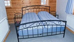 A metal-framed bed with striped bedding in a room with wooden walls and a window.