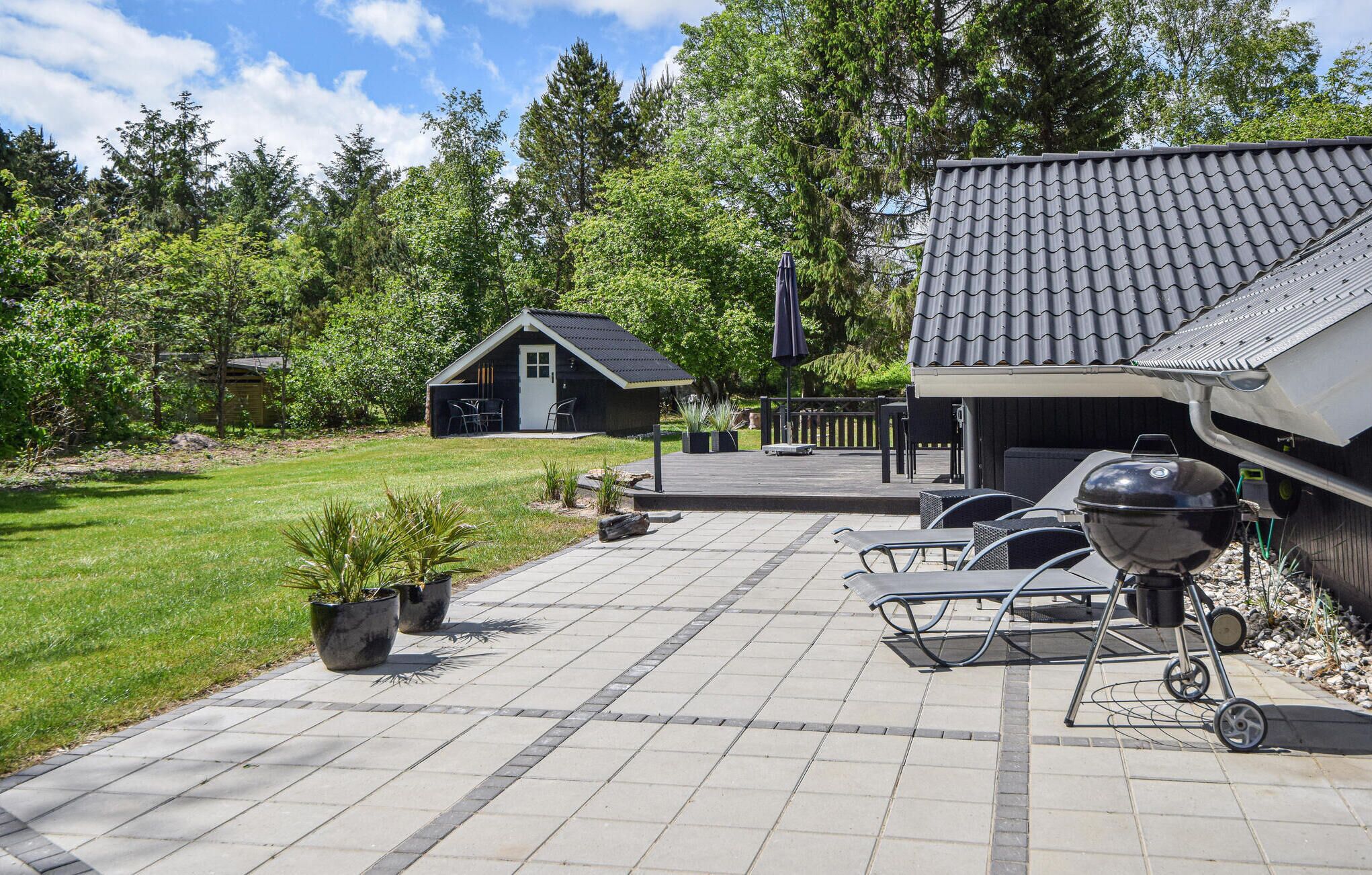 Een terras met een barbecue, zitplaatsen buiten en een kleine schuur.