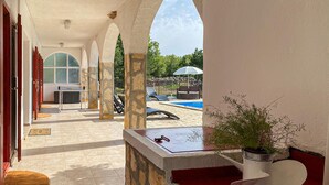 Un espace extérieur abrité, doté d’une piscine, de piliers en pierre et d’une plante en pot.