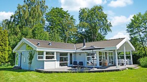 Ett tvåvåningshus med en inglasad veranda, stora fönster och en skorsten.