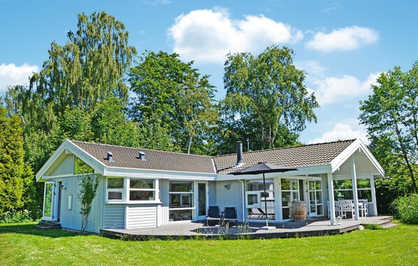 Ein zweistöckiges Haus mit einer Veranda, großen Fenstern und einem Schornstein.