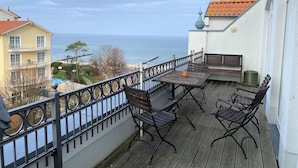 A balcony with a view of the sea, a table with chairs, and a bench. - (76) 3-room apartment with roof terrace lake view - Appartementhaus Atlantik (Kühlungsborn)