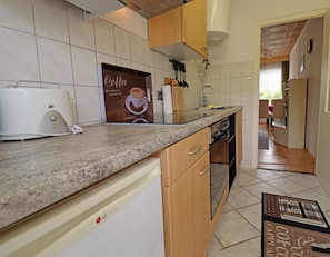A kitchen with a coffee machine, a sink, cabinets, and a countertop.