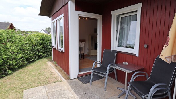 A red building with a patio area featuring two chairs and a small table. - Holiday houses Räuberkuhle 1 - Haus Heringsdorf (Koserow)
