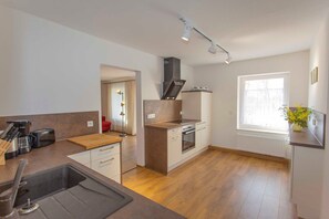 A modern kitchen with a central island, built-in oven, and a window with a view. - House 8 - Rügen-Fewo 280/3 (Dreschvitz)