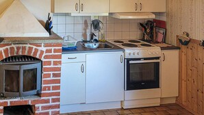 Una cocina compacta con horno de ladrillo, estufa y lavamanos.