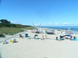 A beach with a sandy path, beach chairs, umbrellas, and a lifeguard stand.
