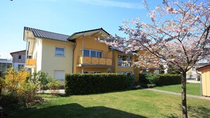 Ein zweigeschossiges Wohnhaus mit Balkon, einem gepflegten Rasen und einer Kirschblüte.
