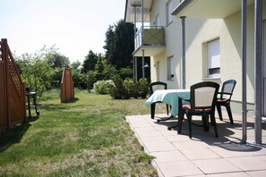 Un patio con una mesa y sillas, una cerca de madera y un edificio con balcón.