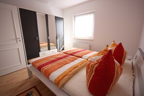 Un dormitorio con cama, armario, ventana y radiador.