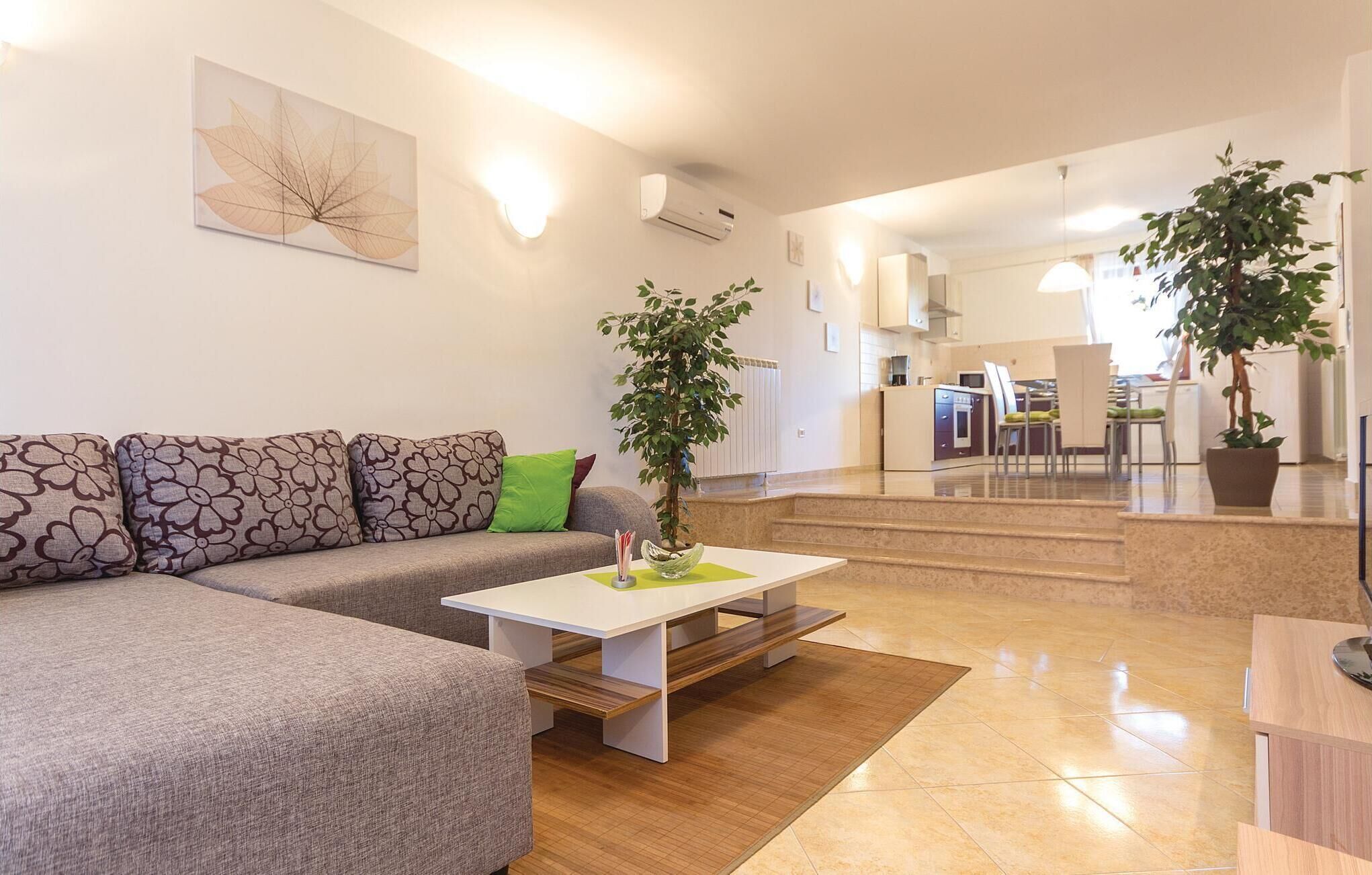 Una sala de estar moderna con un sofá modular, una mesa de centro y dos plantas en macetas.