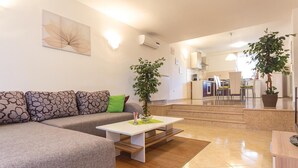 A modern living room with a sectional sofa, a coffee table, and two potted plants. - 2 bedroom nice apartment in Pula (Pula)