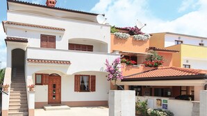 A two-story building with a white facade, wooden shutters, and a tiled roof. - 2 bedroom nice apartment in Pula (Pula)