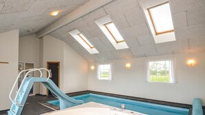 Una piscina interior con tobogán, tragaluces y jacuzzi.
