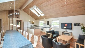 Una cocina moderna con una isla central, un comedor con mantel azul y un área de estar con sofás de cuero.