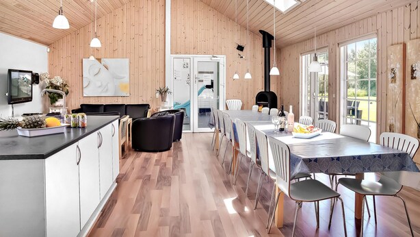 Una cocina moderna con paredes de madera, una zona de comedor con una mesa larga y vistas al exterior.