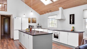 Una cocina moderna con una isla central, armarios blancos y un tragaluz.