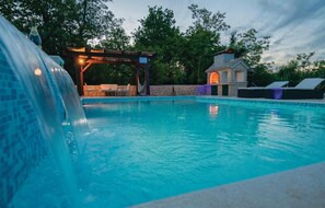 Relax by the serene pool surrounded by a waterfall and lounge chairs.