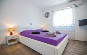 Relax in a serene bedroom with a single bed, tufted headboard, and flat-screen TV.