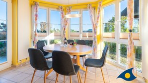 A dining area with a round table, four chairs, a hanging light fixture, and large windows with curtains. - Dune Residence B 05 - DR B 05 (Heringsdorf)