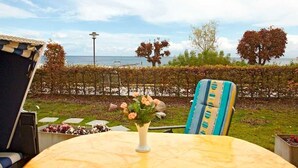 A table with a vase of flowers, a striped chair, and a view of the sea. - Dune Residence B 05 - DR B 05 (Heringsdorf)