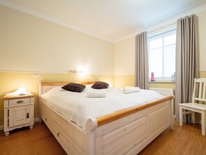 Una camera da letto ordinata con un letto in legno, comodini e una sedia.
