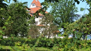 En stor bygning med rødt tag og hvide vægge, omgivet af grøn vegetation.