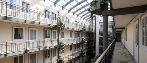 Een meerlaags atrium met balkons, grote ramen en hangplanten.