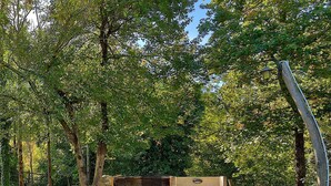 A rustic outdoor seating area with stone benches and a wooden fence, surrounded by lush greenery and trees. - Holiday home for nature lovers in a quiet location (Buzet)