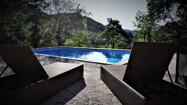 A pool with two lounge chairs facing it, surrounded by trees and hills. - Holiday home for nature lovers in a quiet location (Buzet)